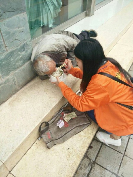 女孩跪地喂老人被指作秀 当事人:做好事为啥这