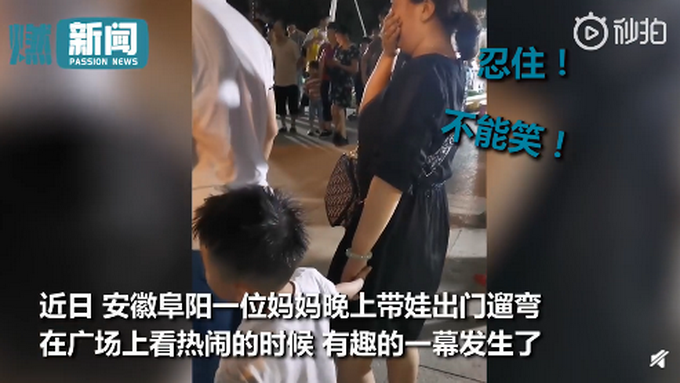 男孩专心看热闹牵错手，陌生阿姨故意不提醒，一手捂住嘴努力憋笑