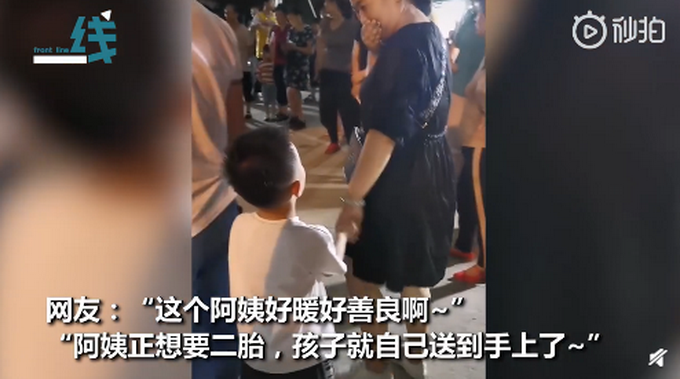 男孩专心看热闹牵错手，陌生阿姨故意不提醒，一手捂住嘴努力憋笑